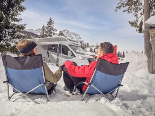 Models relaxing in the snow by their Alora motorhome